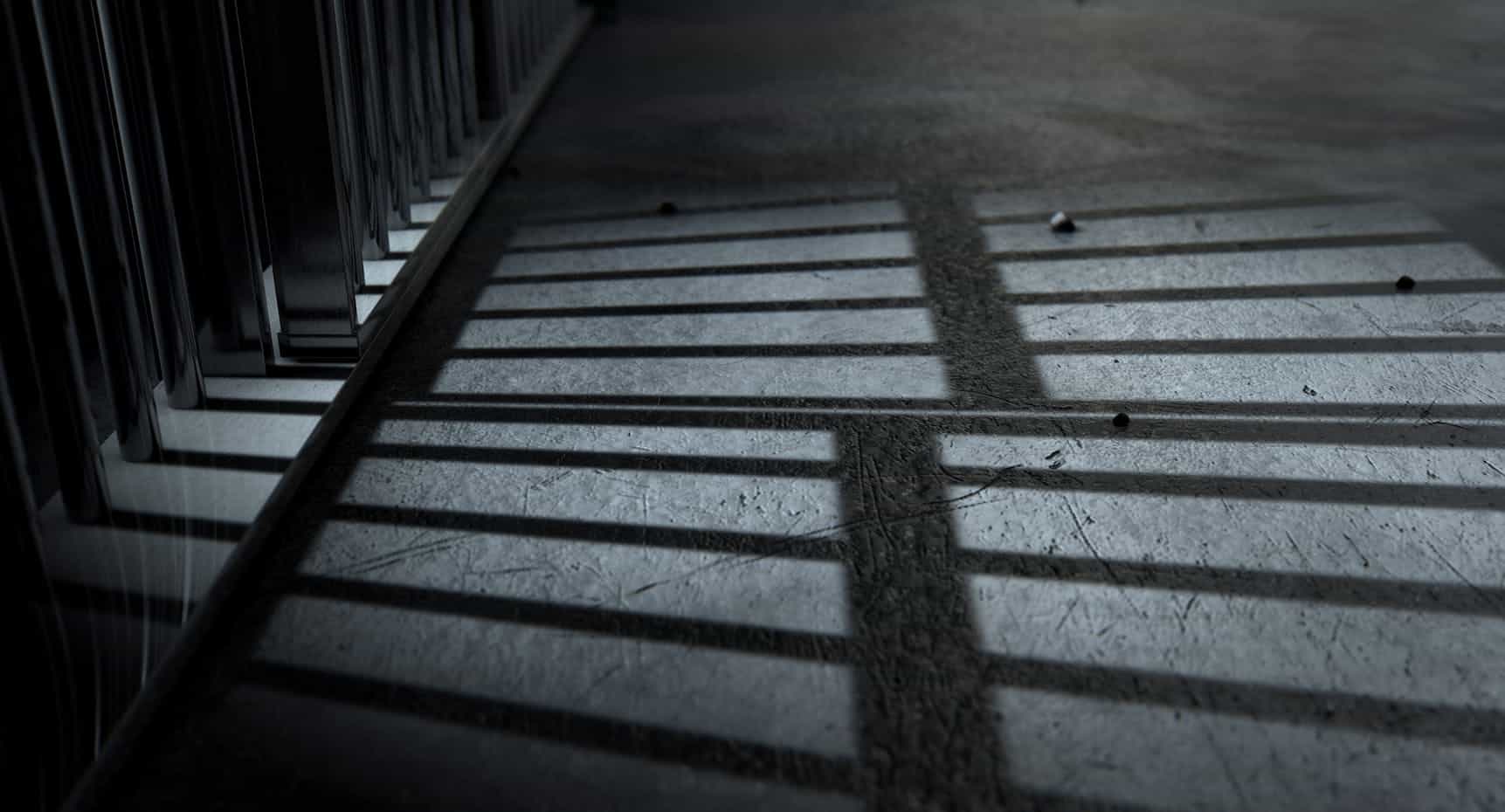 The shadows of prison bars against a grey concrete floor