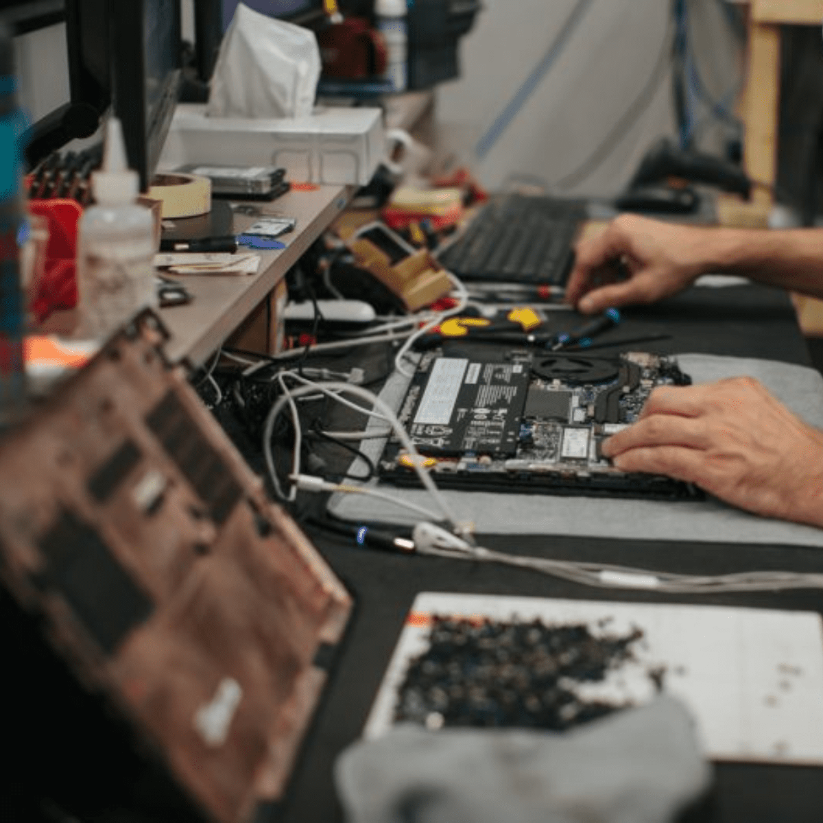 Hands repairing a laptop computer on a workbench