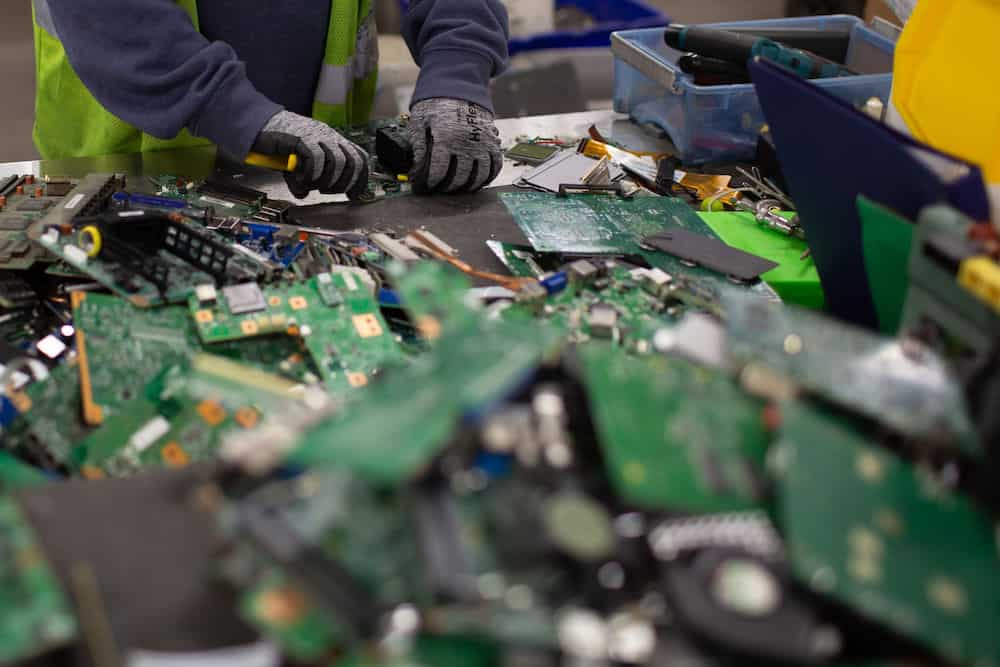 worker processes graphics cards and other electronics at a processing facility for electronic waste recycling